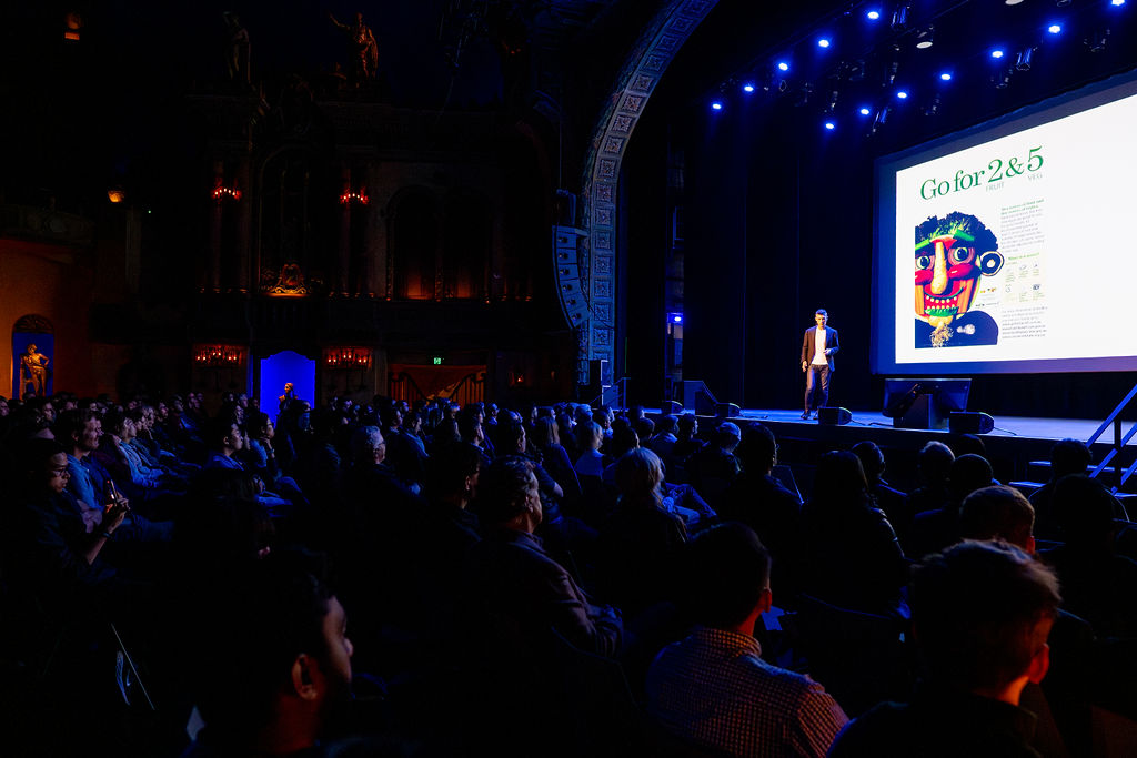 Michael Sankey on stage presenting to a full theatre audience